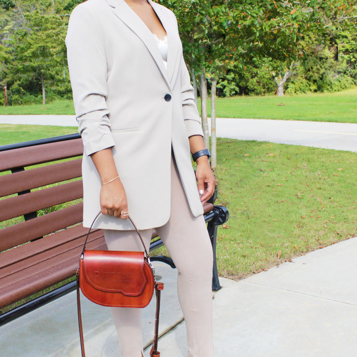 Grace full‑grain vegetable‑tanned leather top‑handle crossbody bag in brown held by a woman with its attached leather strap