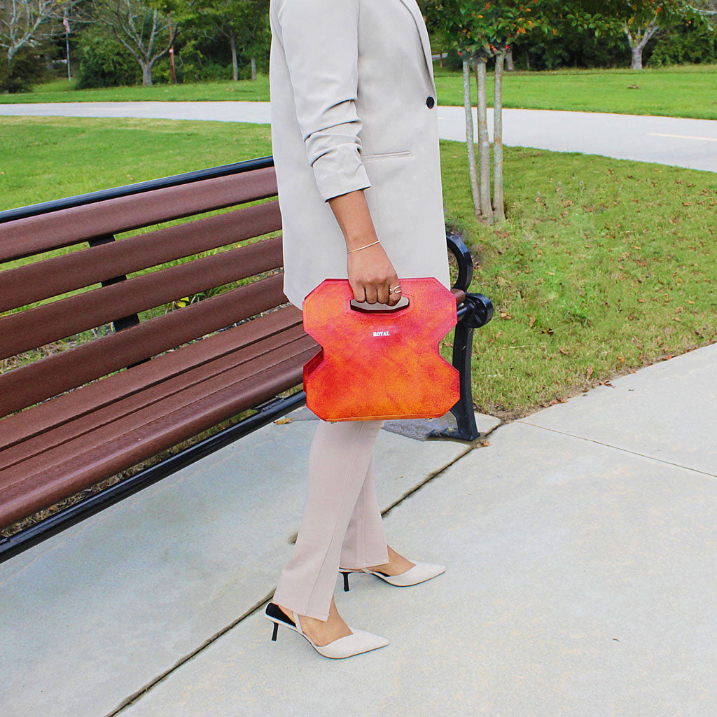 Miracle full‑grain vegetable‑tanned leather cut out handle bag in red with multi‑tone accents held by a woman to highlight the design